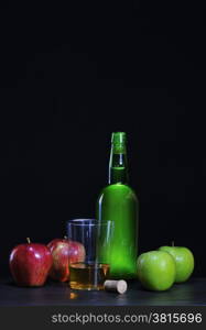 Cider bottle with apples on black background.&#xA;