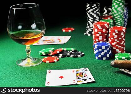Cigar, chips for gamblings, drink and playing cards on green