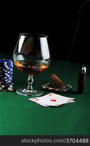 Cigar, chips for gamblings, drink and playing cards on green