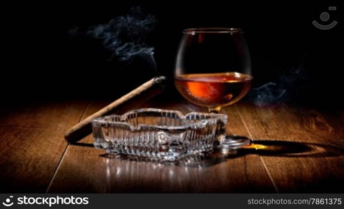 Cigar on ashtray and cognac on a wooden table