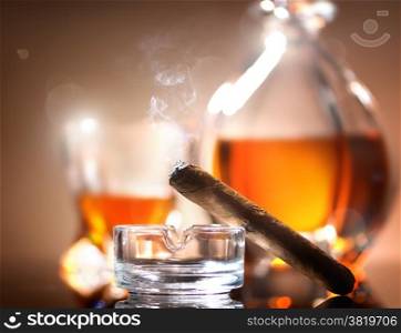 Cigar on ashtray on a background of whiskey