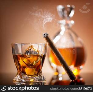 Cigar on glass of whiskey with ice cubes