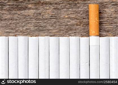 Cigarette addiction concept. Row of cigarettes on a wooden background.