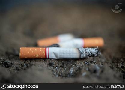 Cigarette burning in outdoors ashtray from smoker addictive nicotine unhealthy and danger concept. Cigarette burning from smoker addictive nicotine