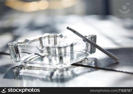 Cigarette in glass ashtray. Horizontal photo