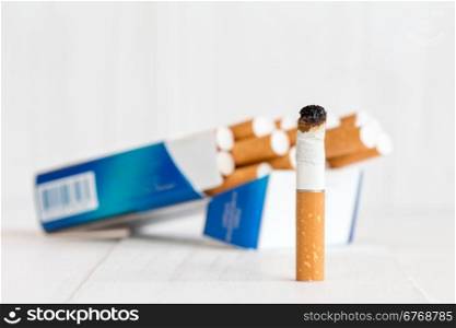 Cigarette package and butt on white wooden background