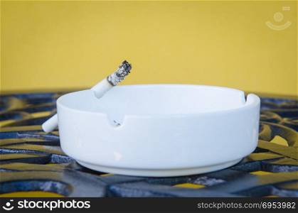 Cigarette smoldering in an ashtray in anticipation of the host