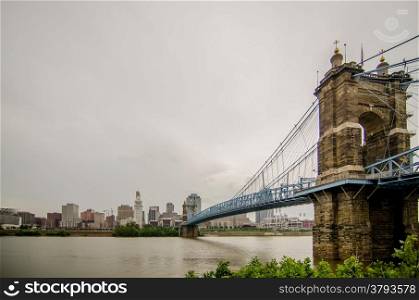 Cincinnati skyline and historic John A. Roebling suspension bridge cross Ohio River.