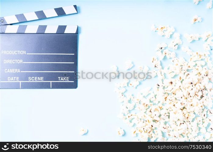 cinema clapper and popcorn over plain blue background, movie and cinema concept, top view. popcorn and 3d glasses