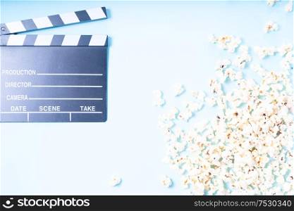 cinema clapper and popcorn over plain blue background, movie and cinema concept, top view. popcorn and 3d glasses