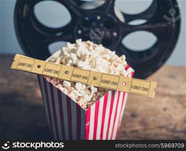 Cinema concept of old film reel with popcorn and movie tickets on a wooden surface