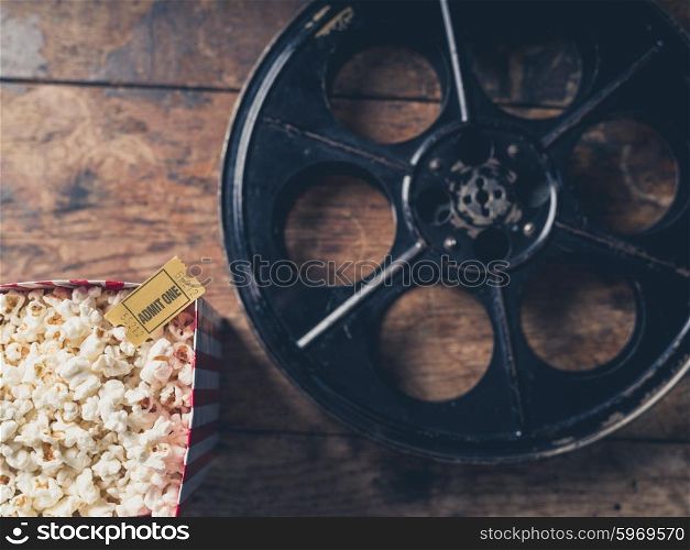 Cinema concept with vintage film reel, popcorn and a movie ticket