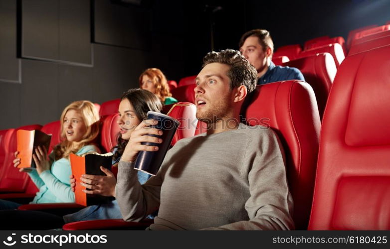 cinema, entertainment and people concept - friends with popcorn and soda watching horror or thriller movie in theater