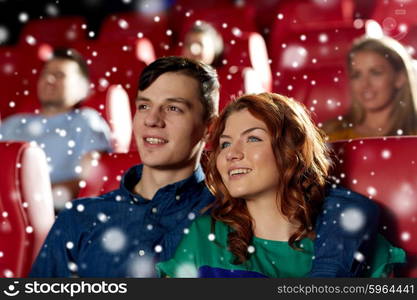 cinema, entertainment and people concept - happy couple watching movie and hugging in theater over snowflakes