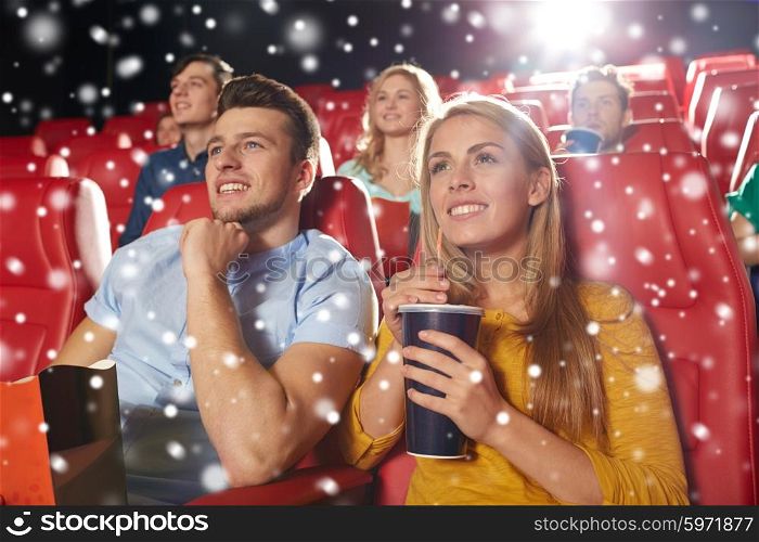 cinema, entertainment and people concept - happy friends or couple with popcorn and lemonade drink watching movie in theater with snowflakes