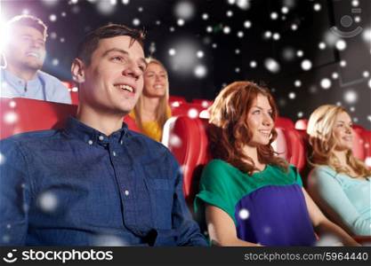 cinema, entertainment and people concept - happy friends watching movie in theater over snowflakes