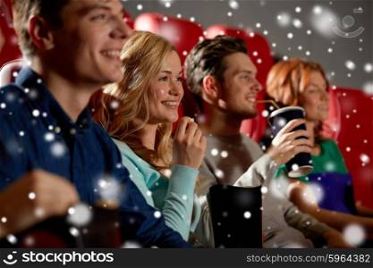 cinema, entertainment and people concept - happy friends with popcorn and lemonade drinks watching movie in theater with snowflakes