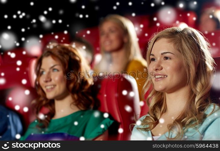 cinema, entertainment and people concept - happy woman with friends watching movie in theater over snowflakes