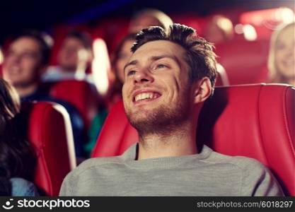 cinema, entertainment and people concept - happy young man watching comedy movie in theater