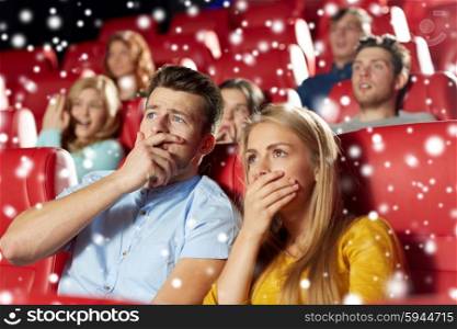 cinema, entertainment and people concept - terrified friends or couple watching horror, drama or thriller movie in theater with snowflakes