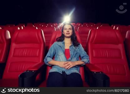cinema, entertainment and people concept - young woman watching movie alone in empty theater auditorium