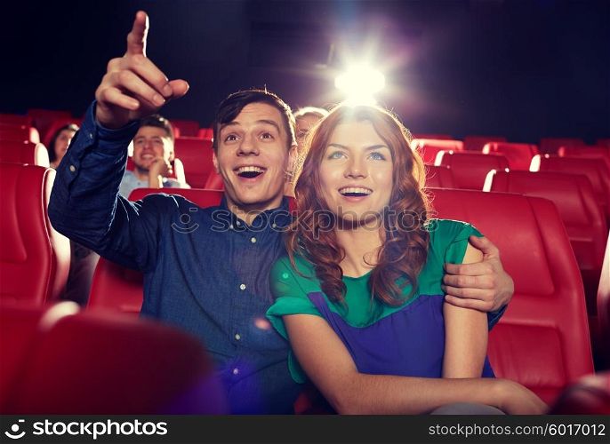 cinema, entertainment, gesture, emotions and people concept - happy friends watching movie pointing finger to screen in theater
