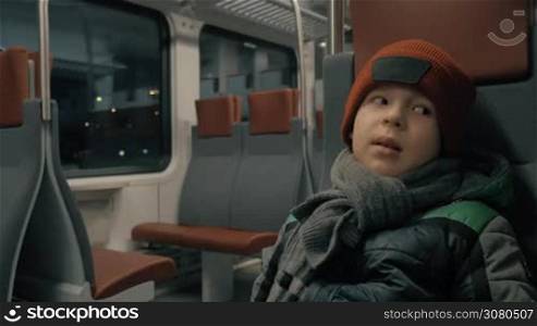 Cinemagraph - Child in traveling by commuter train in winter evening. City lights in darkness in the window