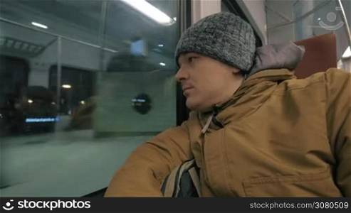 Cinemagraph - Man commuter traveling by train in winter evening. He looking at the station, unidentified passengers reflecting in the window