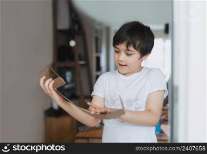 Cinematic portrait Happy young boy using cardboard for headphone toy, Active Kid with big smile while playing card box, Positive child relaxing at home on weekend, DIY Recycling toys idea for Children