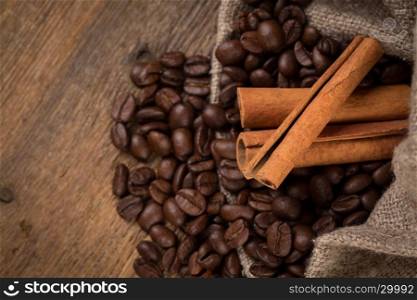 cinnamon sticks and coffee on hessian canvas with wooden background