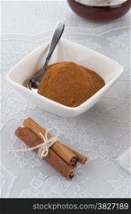 Cinnamon sticks and powder on ceramic bowl.