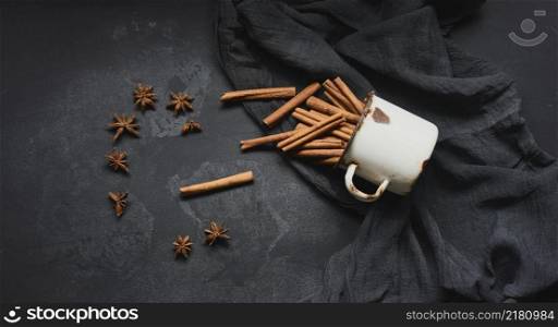 cinnamon sticks in an old metal mug on a black table. Aromatic spice