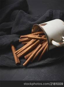 cinnamon sticks in an old metal mug on a black table. Aromatic spice