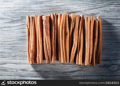Cinnamon sticks isolated on white wooden background. Top view with shadow. Cinnamon sticks isolated on white wooden table