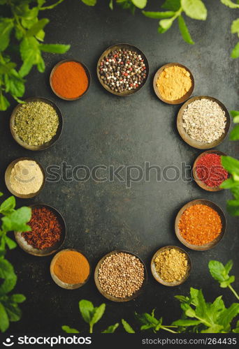 Circle frame composition of spices and herbs over dark background - flat lay. Various bowls of spices over dark background