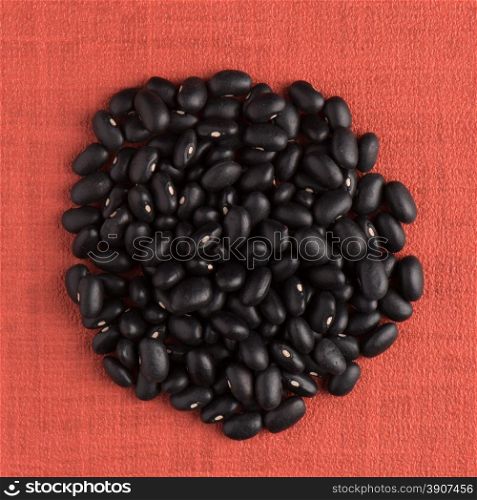Circle of red beans on red vinyl background.