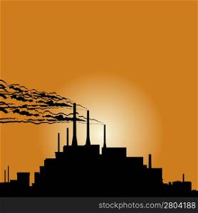 Circuit of industrial buildings and smoking chimneys against the setting sun.