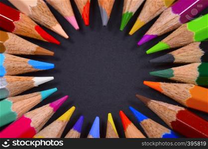 Circular colored pencils on black background