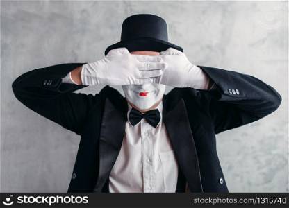 Circus artist posing, pantomime with white makeup mask. Comedy actor in suit, gloves and hat