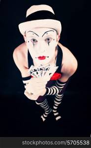 Circus clown in makeup with playing cards on a black background