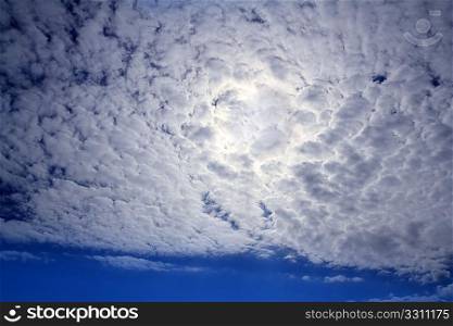 cirrocumulus clouds with sun glowing transparent in blue sky
