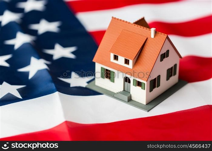 citizenship, residence, property, real estate and people concept - close up of living house model over american flag