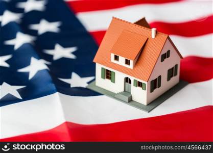 citizenship, residence, property, real estate and people concept - close up of living house model over american flag