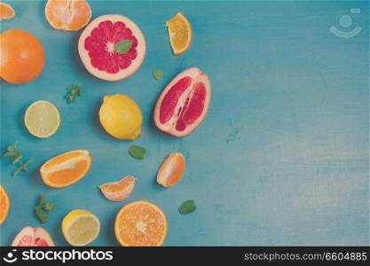 citrus food border on blue background - assorted citrus fruits with mint leaves, retro toned. citrus pattern on blue
