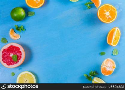 citrus food close up frame pattern on blue background - assorted citrus fruits with mint leaves. citrus pattern on blue