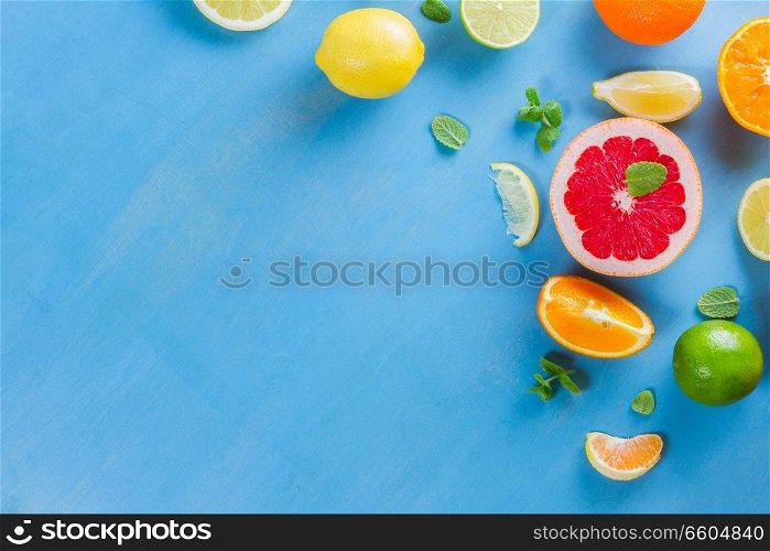 citrus food flat lay border pattern on blue background - assorted citrus fruits with mint leaves. citrus pattern on blue