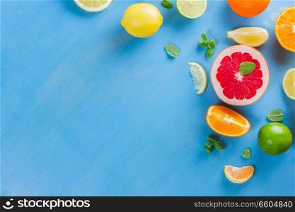 citrus food flat lay border pattern on blue background - assorted citrus fruits with mint leaves. citrus pattern on blue