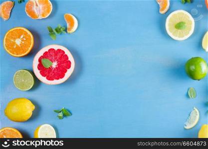 citrus food flat lay frame pattern on blue background - assorted citrus fruits with mint leaves. citrus pattern on blue