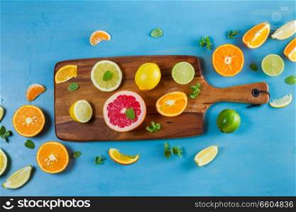 citrus food pattern on blue background - assorted citrus fruits with mint leaves on cutting board. citrus pattern on blue