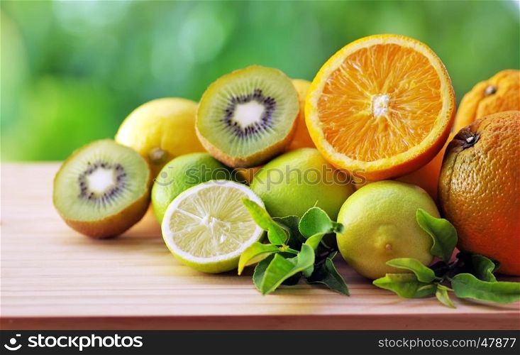 Citrus fruits, kiwis and leaves on table